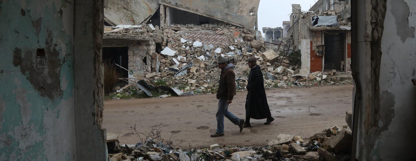 Deux personnes marchent parmi les vestiges bombardés du village de Bara, dans l'ouest de la Syrie.