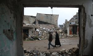Deux personnes marchent parmi les vestiges bombardés du village de Bara, dans l'ouest de la Syrie.
