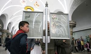 Commuters read newspapers in a metro station in Pyongyang, DPRK.