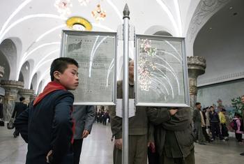 Commuters read newspapers in a metro station in Pyongyang, DPRK.