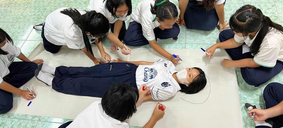 Des camarades de classe dessinent autour du corps d'une élève dans une école du nord de la Thaïlande.