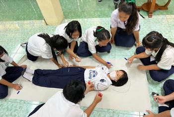 Class mates draw around the body of a student at a school in northern Thailand.