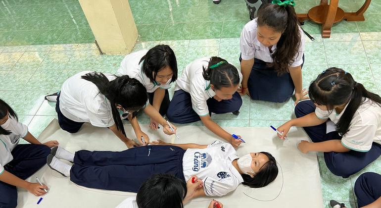 Class mates draw around the body of a student at a school in northern Thailand.