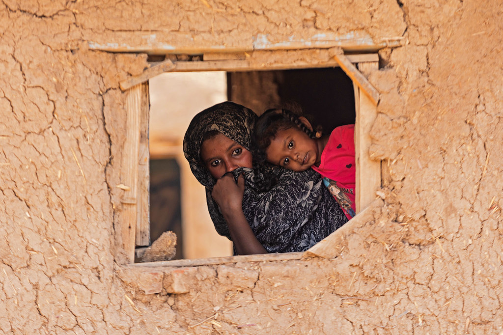 Un enfant et sa mère regardent à travers une fenêtre dans la communauté d'Alsabaat, dans l'État de Kassala.