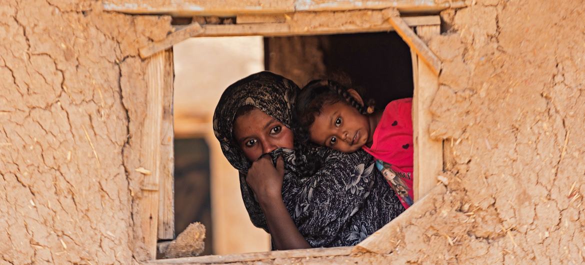 A child and mother peer through a window in Alsabaat community, Kassala state.