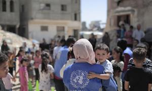 Una trabajador de UNRWA lleva a un niño en Gaza.