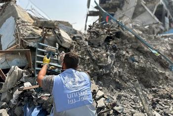 An UNRWA worker sifts through rubble in gaza.