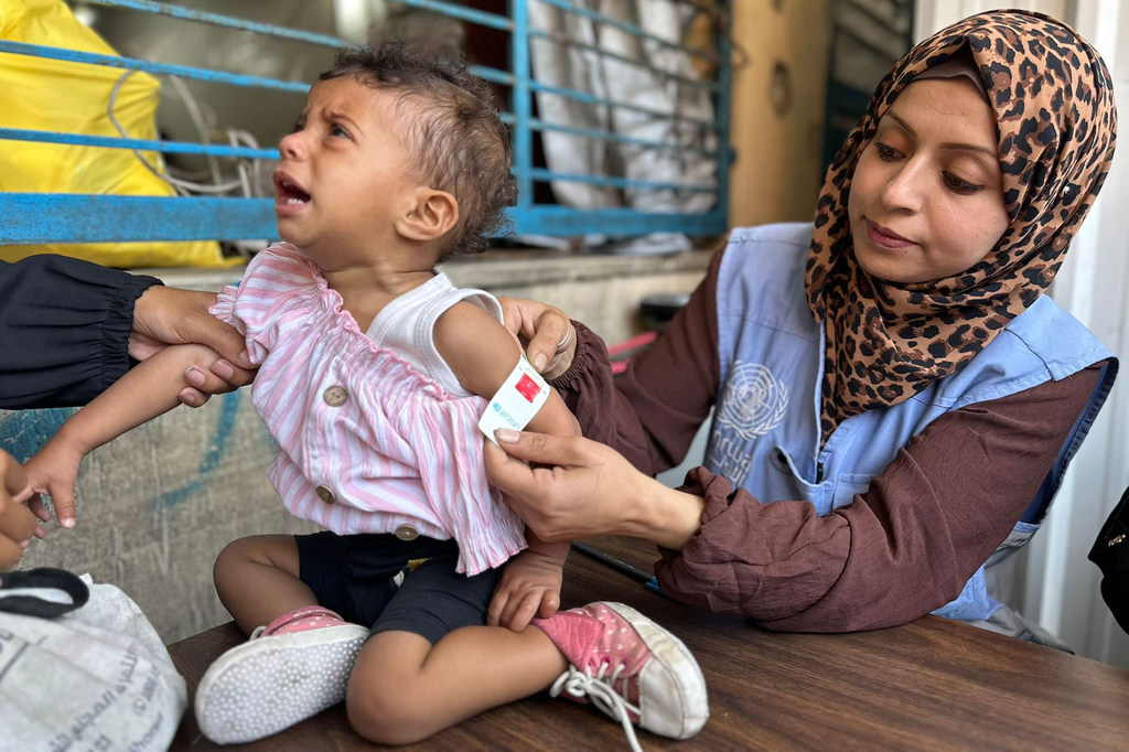 Une employée de l'UNRWA à Gaza examine un enfant pour détecter des signes de malnutrition.