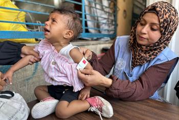 An UNRWA worker in Gaza checks a child for signs of malnutrition.
