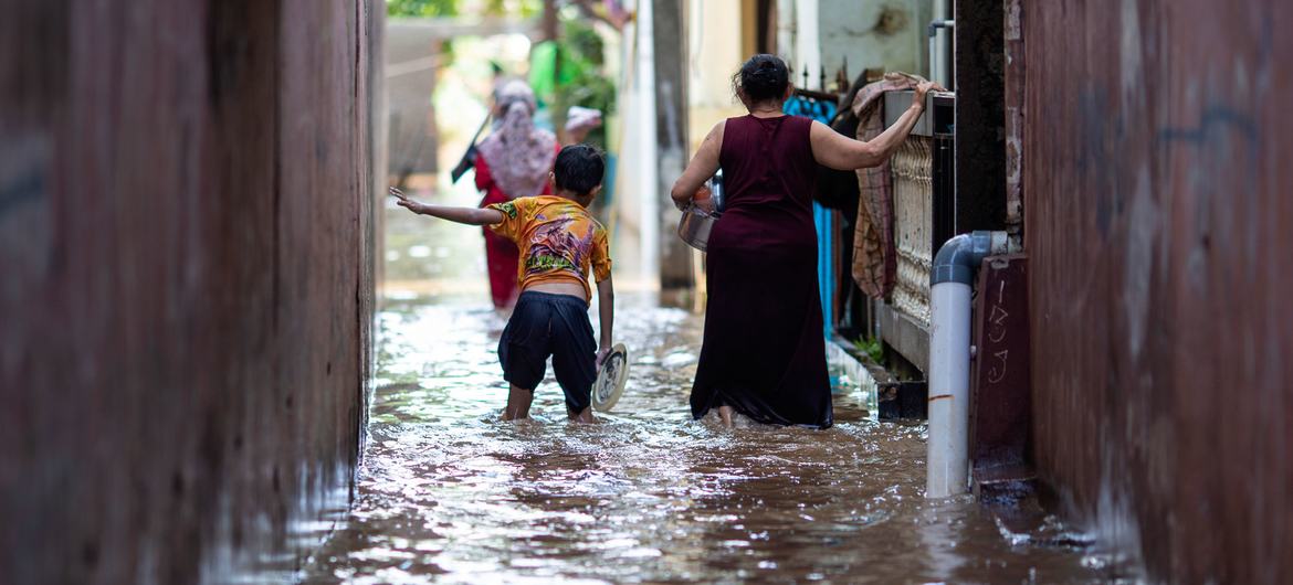 Un garçon et sa mère marchent dans une zone inondée à Jakarta, en Indonésie, en février 2021.