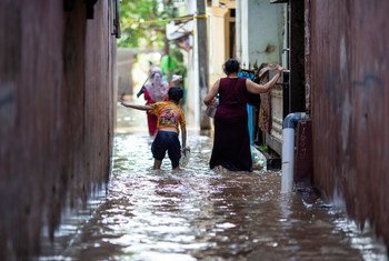 इण्डोनेशिया की राजधानी जकार्ता में एक बाढ़ प्रभावित इलाक़े में एक माँ अपने बच्चे के साथ.