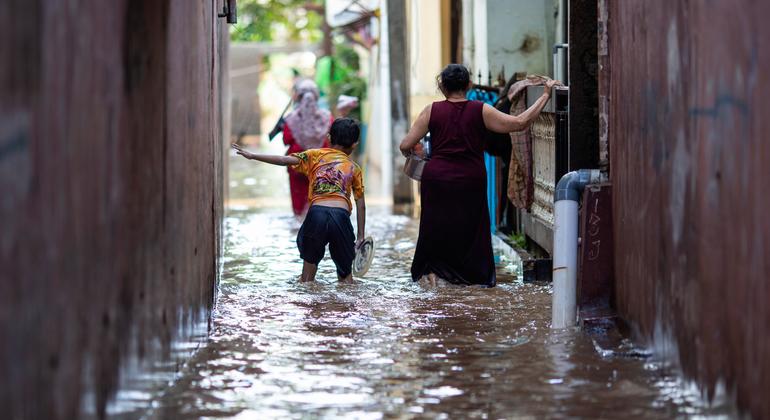 A boy and his mother walk through a flooded area in East Jakarta, Indonesia. in February 2021.