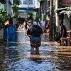 A woman walks through water in an area affected by flooding in East Jakarta, Indonesia.