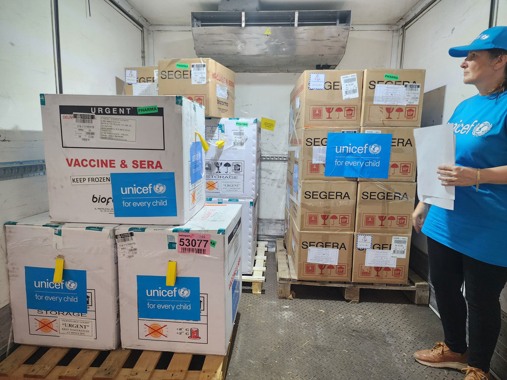 عاملة في UNICEF ترتدي زياً أزرق تقف بجوار صناديق لقاح شلل الأطفال في شاحنة مبردة في غزة.