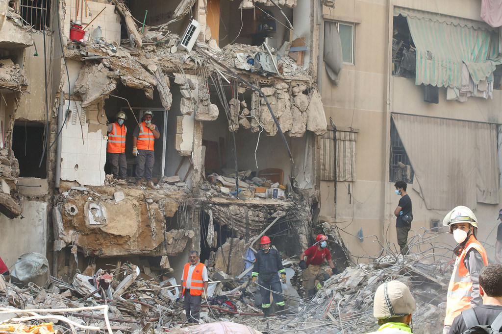 Des secouristes examinent les dégâts causés par un missile sur un immeuble de la banlieue sud de Beyrouth.