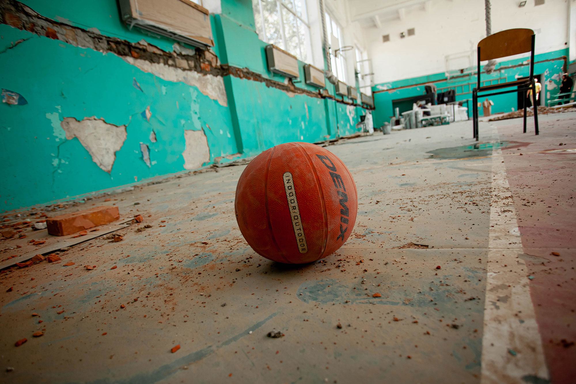 Un ballon de basket abandonné dans le gymnase d'une école endommagée lors d'intenses bombardements dans la région de Kherson, en Ukraine.