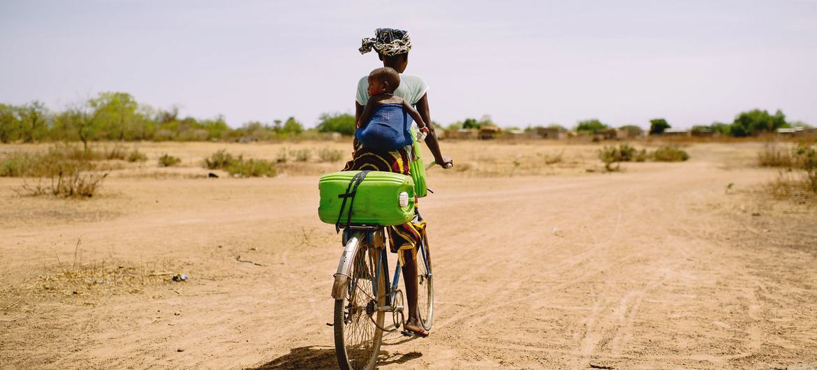 Mulher busca água de bicicleta perto de Boromo, em Burkina Faso.