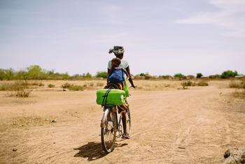 Mulher busca água de bicicleta perto de Boromo, em Burkina Faso.