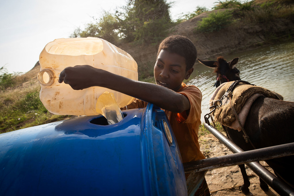 在苏丹南部白尼罗州，一名男孩从修复后的集水池取水。