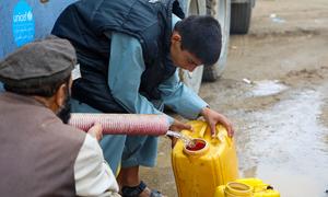 Pessoas na região central do Afeganistão coletam água de caminhão depois que suas casas foram levadas pelas enchentes.