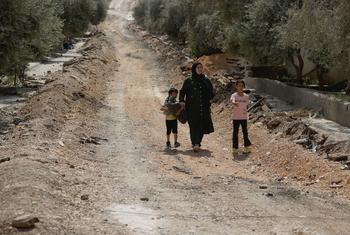 一名妇女和两个孩子在约旦河西岸杰宁市附近行走。