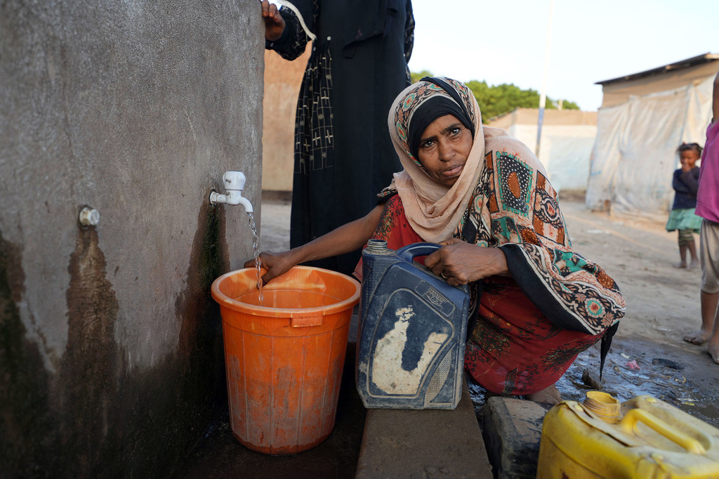 A woman collects water at a camp for people displaced by conflict in Yemen.