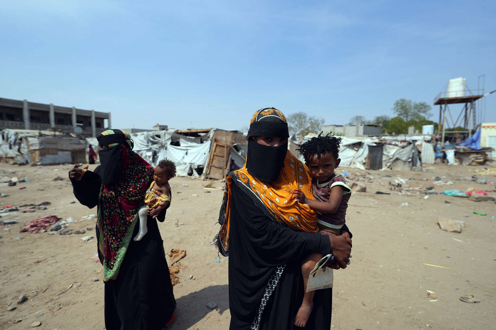 Mujeres cargando a sus hijos en un campo de desplazados por la violencia en Yemen.