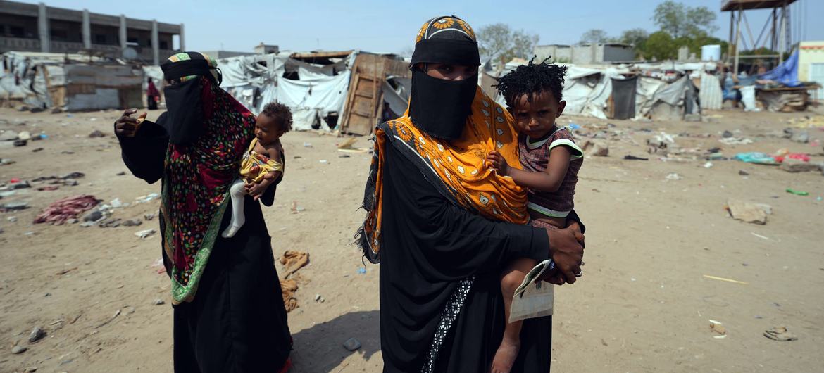 Mujeres cargando a sus hijos en un campo de desplazados por la violencia en Yemen.