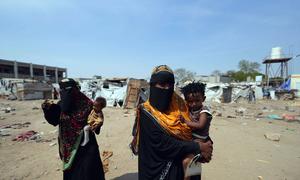Mujeres cargando a sus hijos en un campo de desplazados por la violencia en Yemen.