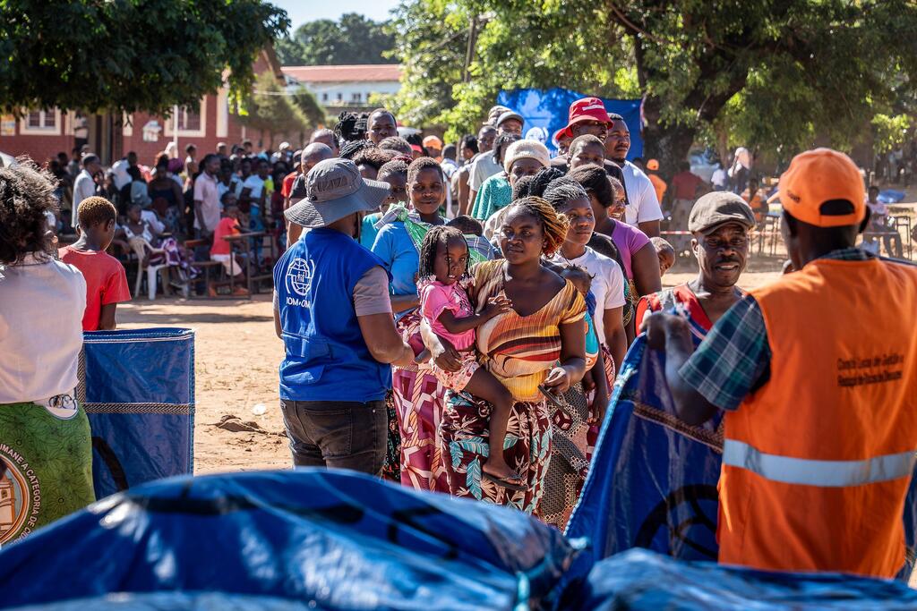 Umati wa watu waliokimbia makazi yao nchini Msumbiji, wakiwemo wanawake na watoto, wanapokea msaada kutoka kwa wafanyakazi wa IOM wakati wa operesheni ya kutoa msaada kutokana na mafuriko.