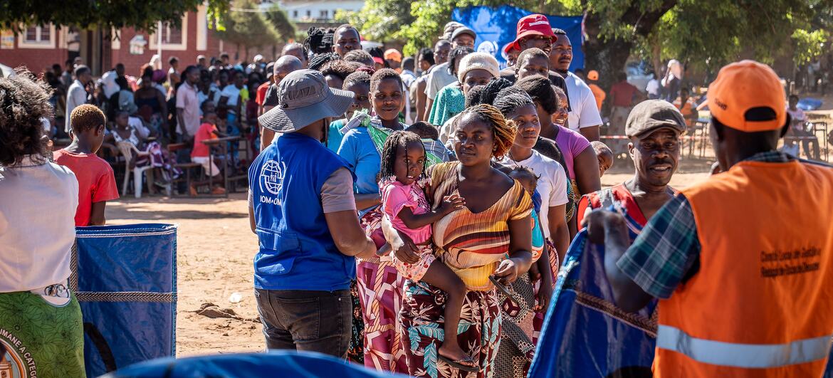 Uma multidão de pessoas deslocadas em Moçambique, incluindo mulheres e crianças, recebem ajuda de trabalhadores da OIM durante uma operação de socorro de inundações.