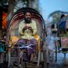 Un tireur de rickshaw au Bangladesh est assis dans son rickshaw et compte ses gains, qui semblent être des billets Taka du Bangladesh.