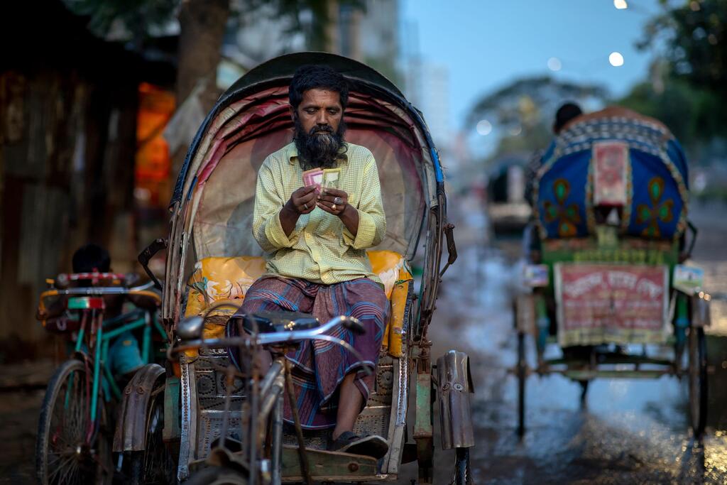 Un homme compte les gains de sa journée sur son rickshaw à Dhaka, au Bangladesh.