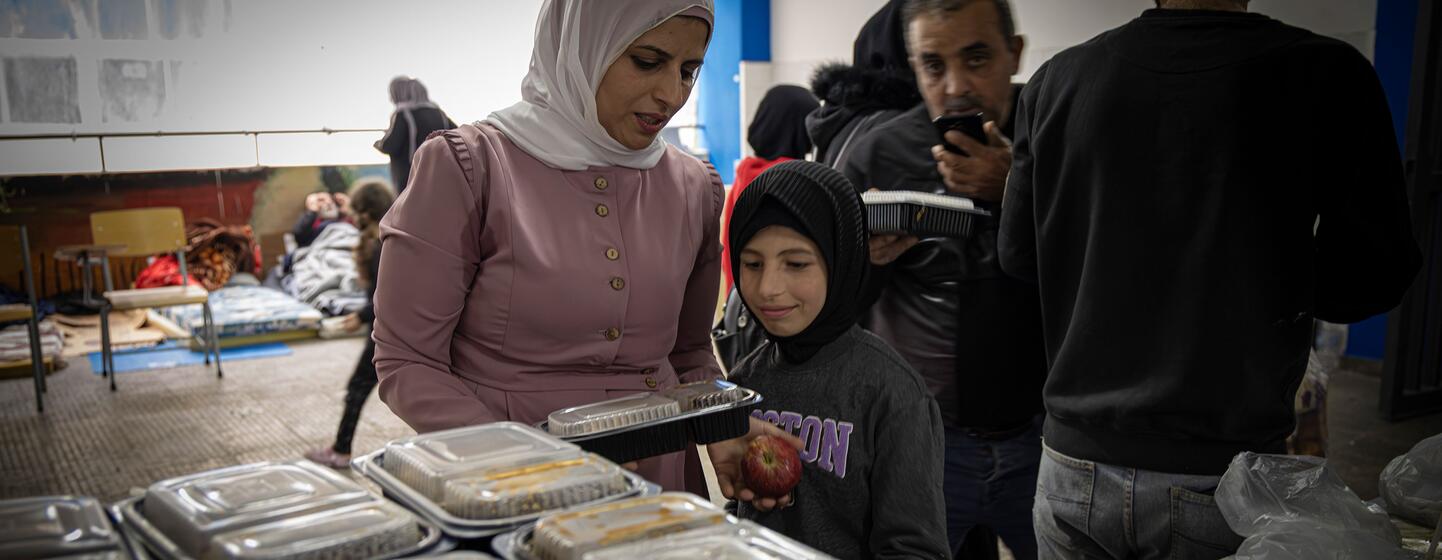Une femme et une jeune fille reçoivent des conteneurs de nourriture dans un centre de distribution dans une école de Beyrouth.