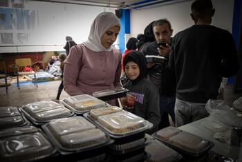 Une femme et une jeune fille reçoivent des conteneurs de nourriture dans un centre de distribution dans une école de Beyrouth.