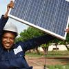 A teenage woman in Côte d'Ivoire holds up a solar panel which she is studying as part of a renewable energy course.
