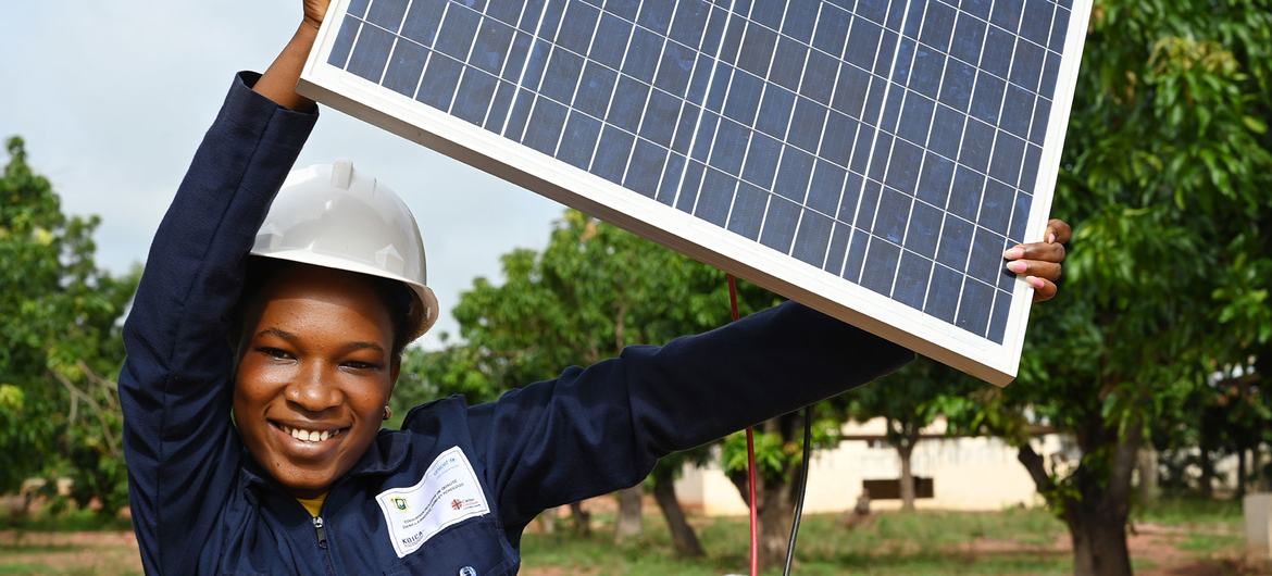 En Côte d'Ivoire, une adolescente brandit un panneau solaire qu'elle étudie dans le cadre d'un cours sur les énergies renouvelables.