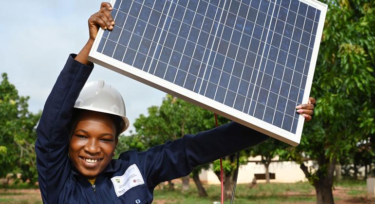 A teenage woman in Côte d'Ivoire holds up a solar panel which she is studying as part of a renewable energy course.