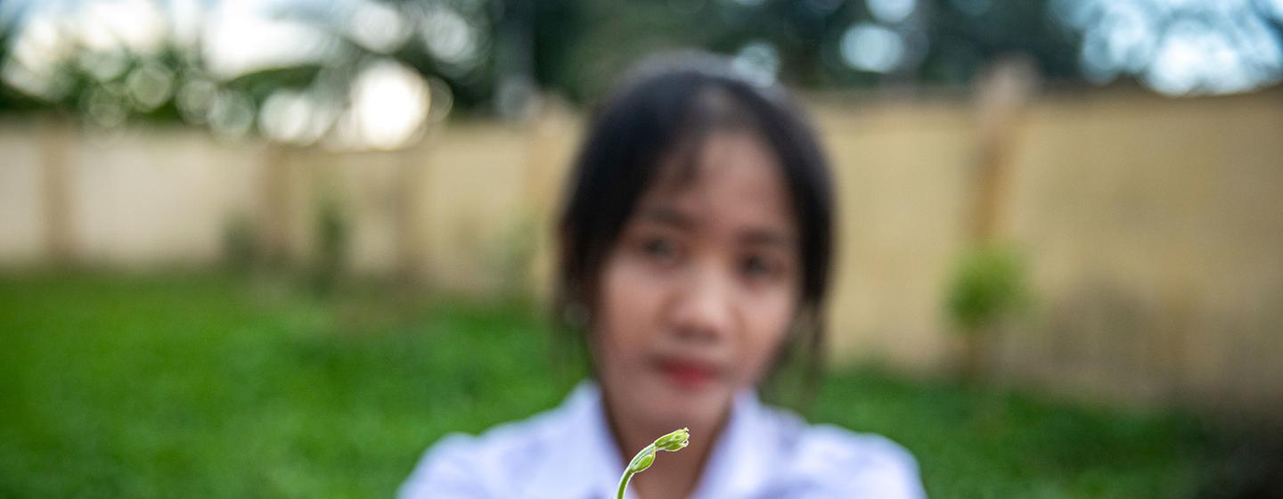 A student in Viet Nam presents a seedling.