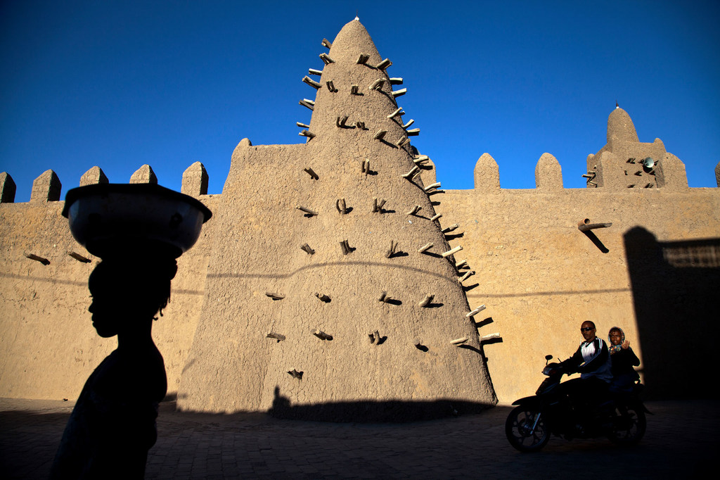 Residents of Timbuktu pass by Djingareyber Mosque, among the historical architectural structures that earned the city the designation of a UNESCO World Heritage Site.