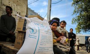 Una familia palestina recibe la ayuda alimentaria de la ONU en un centro de distribución de Nusierat, Gaza (enero de 2025).