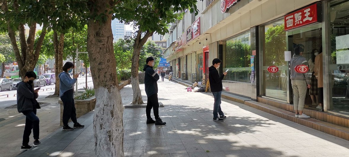 新冠疫情期间，中国深圳的人们在排队等待外卖时，自觉地保持一定距离。
