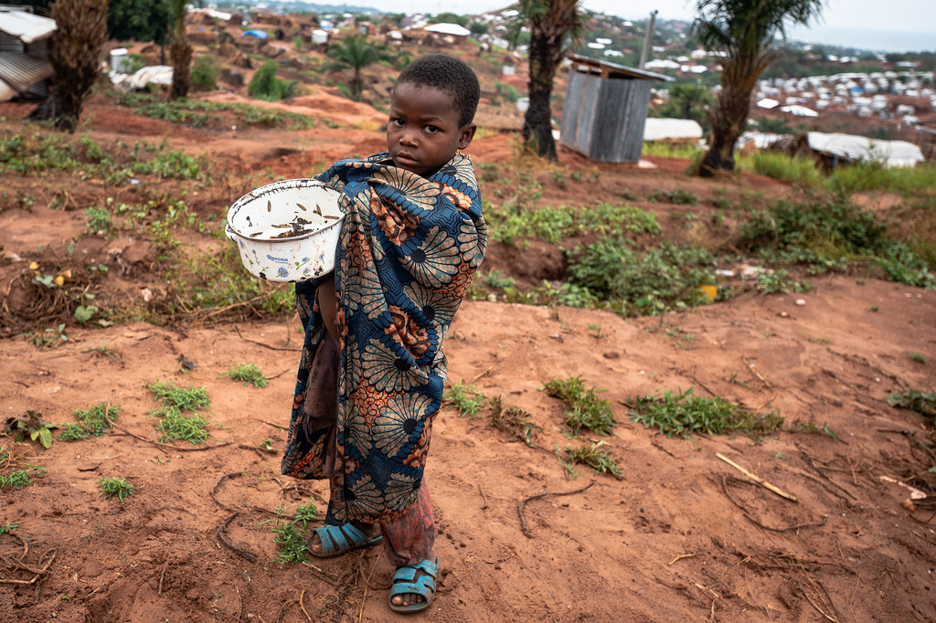 Un enfant tient une casserole de criquets dans un camp pour personnes déplacées en République démocratique du Congo.