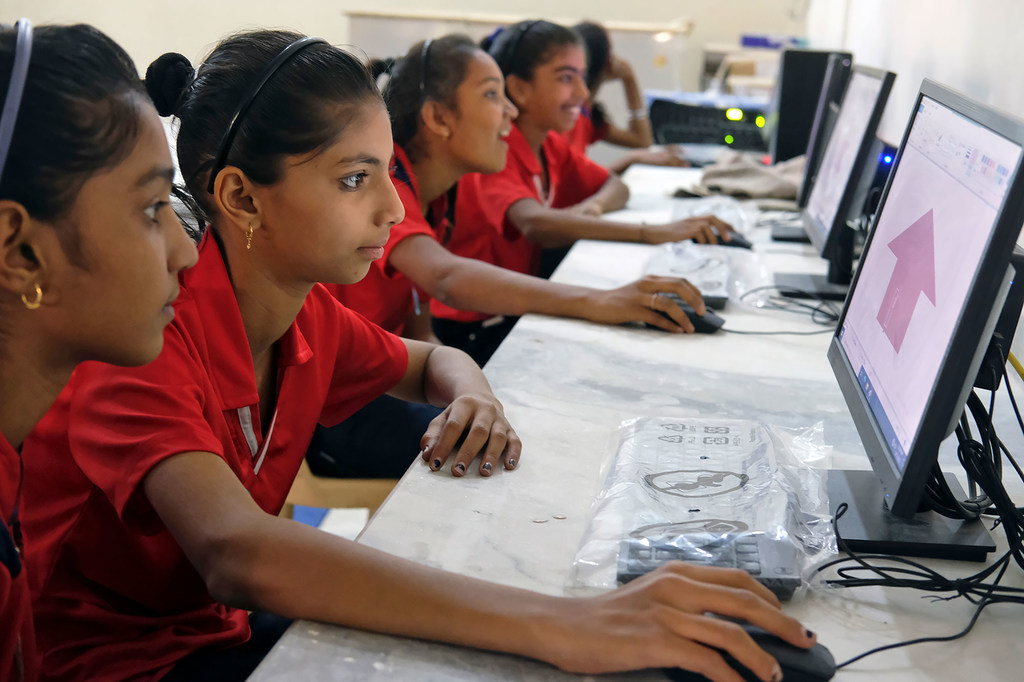 Adolescentes aprendiendo a desarrollar habilidades digitales en una escuela primaria en India.