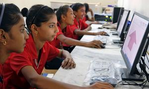 Adolescent girls learn computer skills at a primary school in India.