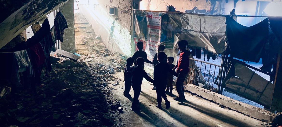 A family walks through an area where people are sheltering in the remains of a bombed building in Gaza.