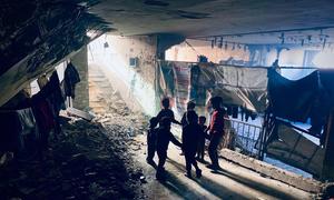 A family walks through an area where people are sheltering in the remains of a bombed building in Gaza.