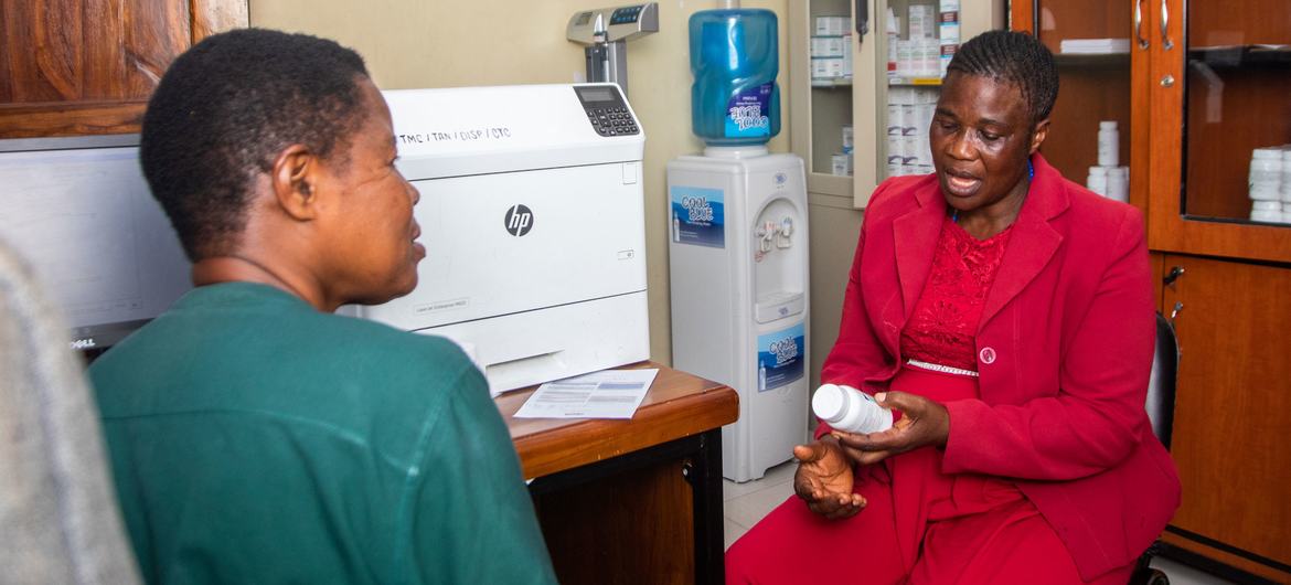 Elizabeth Sangu, defensora do tratamento, recebe sua medicação de uma enfermeira no Centro de Tratamento Comunitário (CTC) de Tambukareli, em Dar es Salaam, Tanzânia, no Dia Mundial da Luta contra a AIDS.
