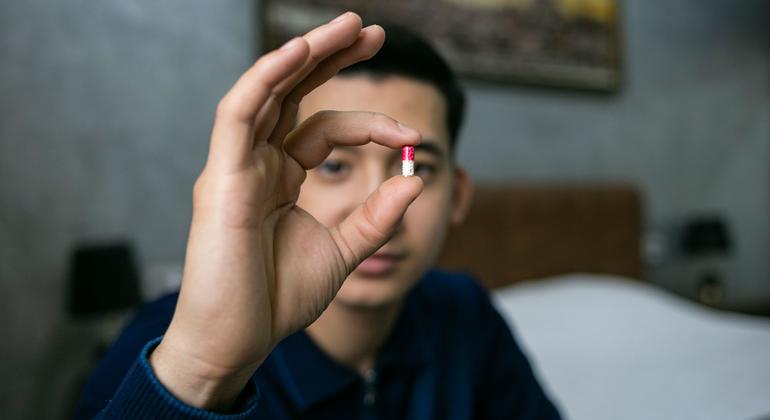 Um homem no Uzbequistão mostra o medicamento que toma para combater o HIV