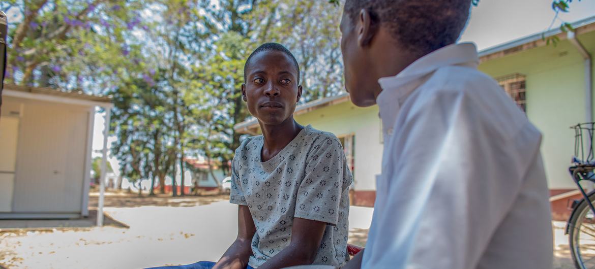 Un consejero especializado en la adherencia al tratamiento del VIH habla con un adolescente que participa en su tratamiento al aire libre en el Hospital del Distrito de Makhumbe en Zimbabue.